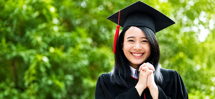 A smiling young woman wearing a graduation cap and gown